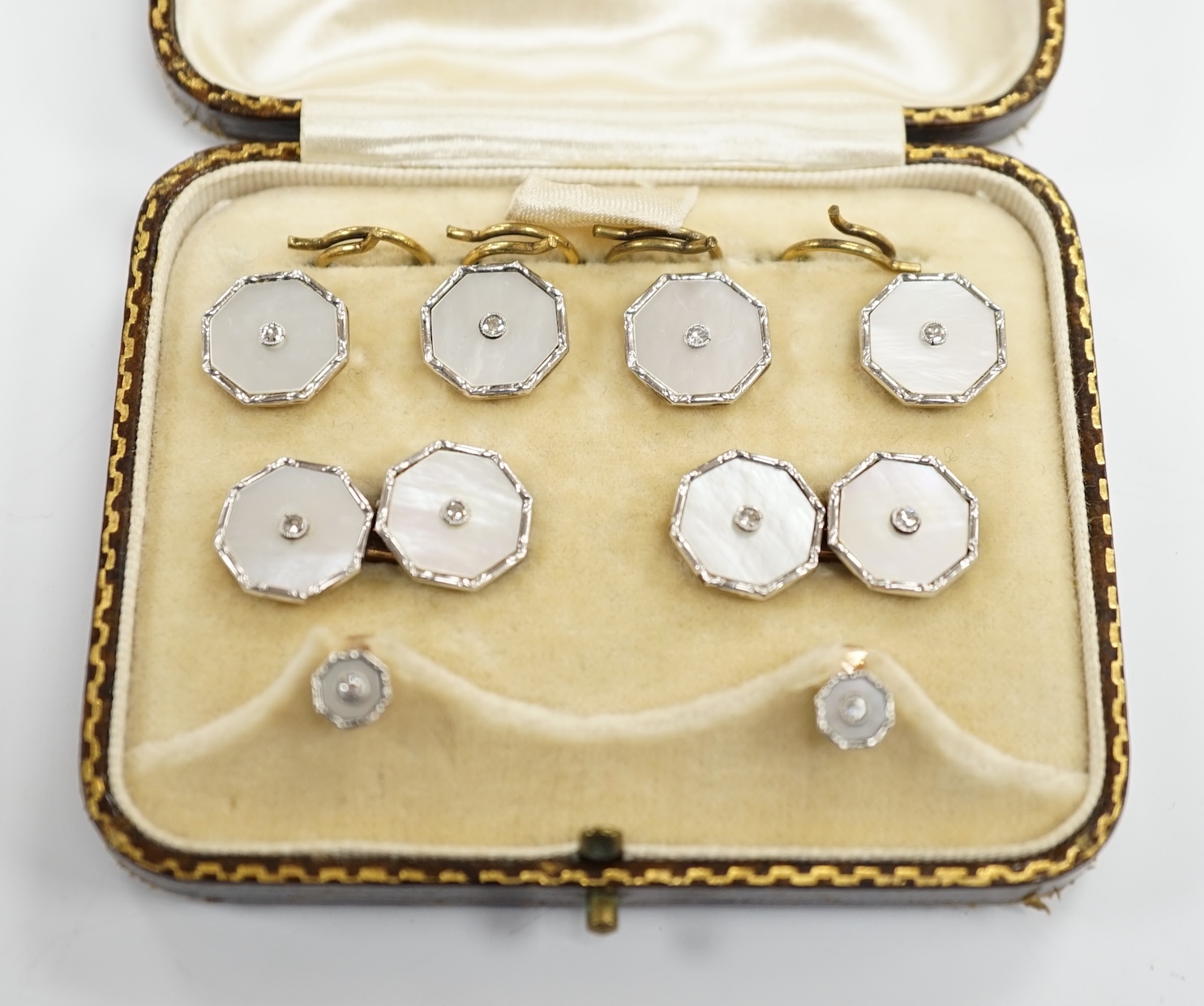 A cased eight piece 9ct, mother of pearl and diamond chip set dress stud set.